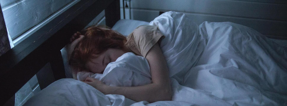 Eine Frau, die in ihrem Bett eingekuschelt am Schlafen ist