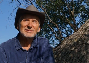 Ein Mann mit einem Hut vor einem Baum