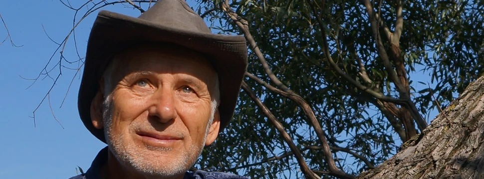 Ein Mann mit einem Hut vor einem Baum