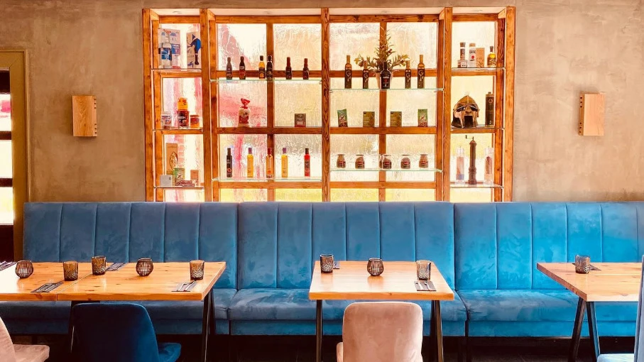 Innenansicht des Restaurants Filoxenia Innenansicht eines Raums mit weißen Stühlen, einem Regal und einem blauen Sofa
