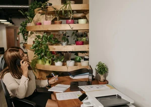 Frau sitzt im Büro am Schreibtisch und telefoniert