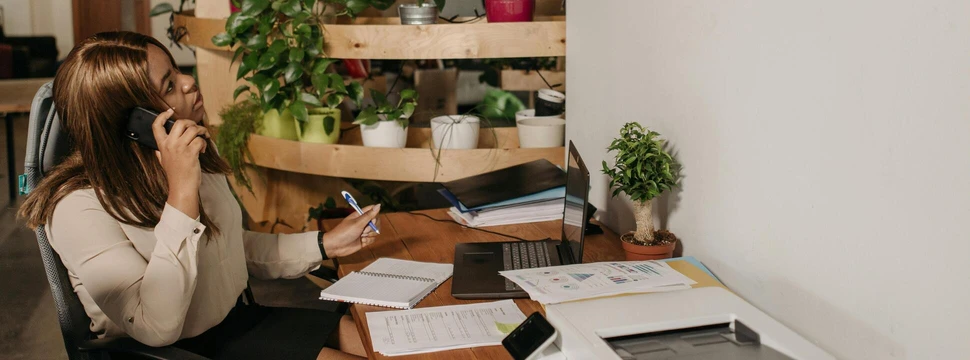 Frau sitzt im Büro am Schreibtisch und telefoniert
