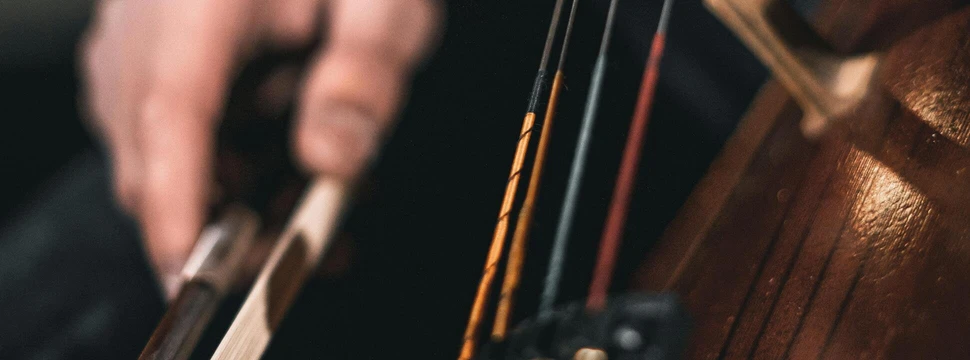 Eine Hand in einem roten Gewand mit einem Cellebogen in der Hand