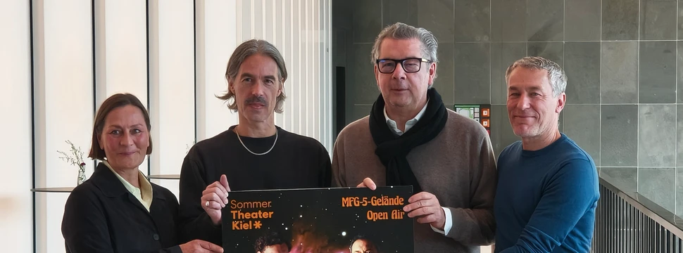 Vier Menschen mit einem Plakat in der Hand, auf dem das Theaterstück "Faust" vorgestellt wird, das im Sommer auf dem MFG-5 Gelände in Holtenau aufgeführt wird