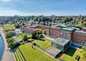 Der Landtag aus Schleswig-Holstein aus der Luft gesehen Ein Backsteingebäude an der Kieler Förde aus der Luft gesehen mit Wasser im Vordergrund und Bäumen im Hintergrund
