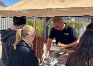 Mehrere Menschen vor einem Eisstand, an dem zum Schuljubiläum Eis verteilt wurde