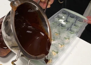 Schokolade, die in einer Schüssel sich befindet, wird in eine Form aus Gummi gegossen