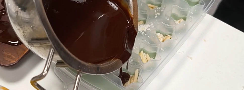 Schokolade, die in einer Schüssel sich befindet, wird in eine Form aus Gummi gegossen