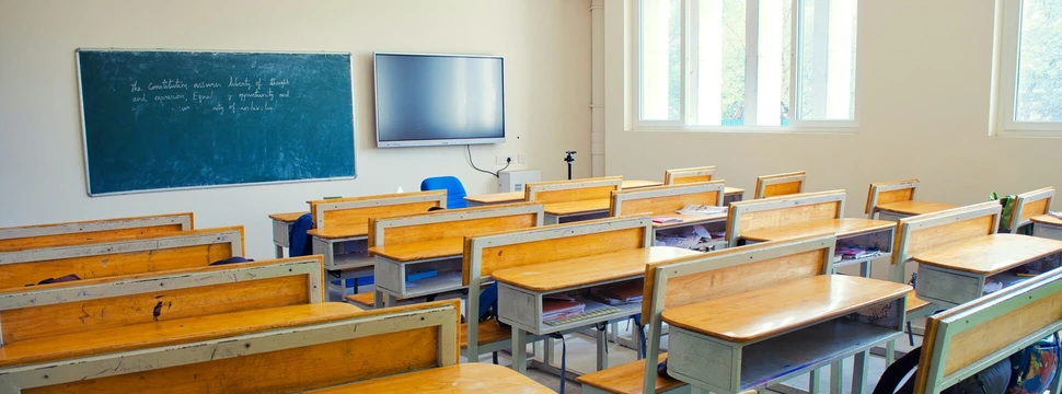 Schulbänke sind diagonal zu einer Tafel aufgestellt