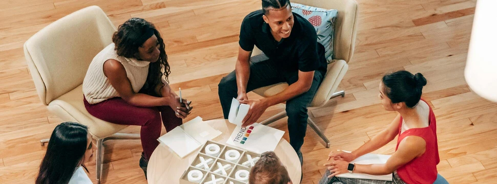 Mehrere Menschen, die um einen Tisch sitzen und sich austauschen