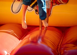 Unterkörper eines Kindes ist im Sprung. Im Hintergrund sieht man ein Sprungraum