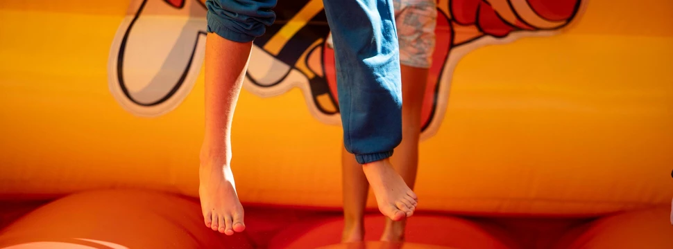 Unterkörper eines Kindes ist im Sprung. Im Hintergrund sieht man ein Sprungraum