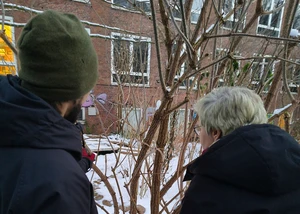 Zwei Menschen, die bei Schnee vor einem Baum stehen