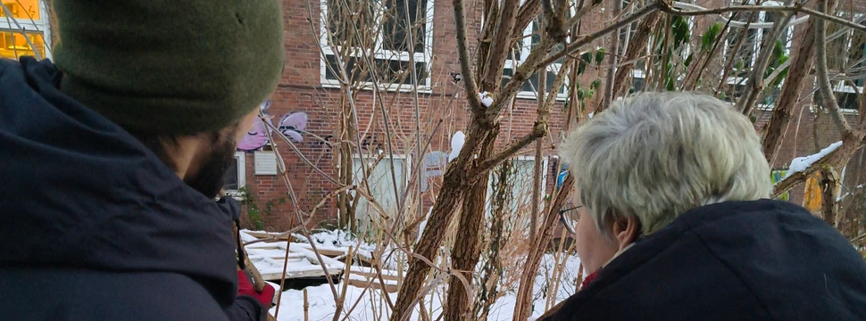 Zwei Menschen, die bei Schnee vor einem Baum stehen
