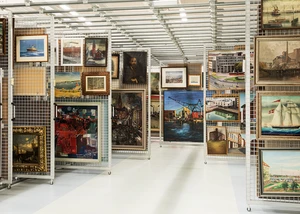 Kunstwerke dicht gehängt auf aufziehbaren Gittern im Lager