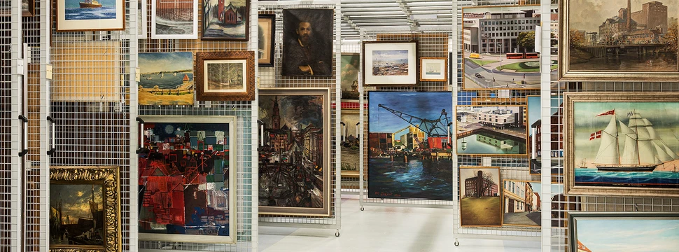 Kunstwerke dicht gehängt auf aufziehbaren Gittern im Lager