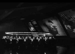 Eine Konferenz, bei der mehrere Menschen an einem Tisch sitzen und diskutieren. Das Bild ist in Schwarz-Weiß gehalten