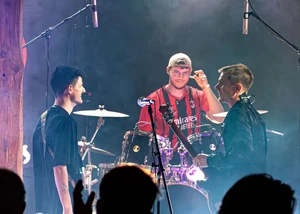 Drei Männer, die auf einer Bühne einen Auftritt haben