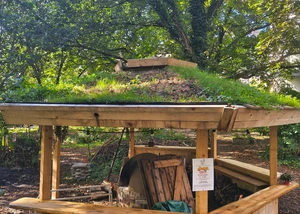 Das Dach des Pavillons in der Alten Mu mit entsprechender Dachbegrünung Ein Pavillon aus Holz mit einem Lehmbackofen in der Mitte und einer Dachbegrünung