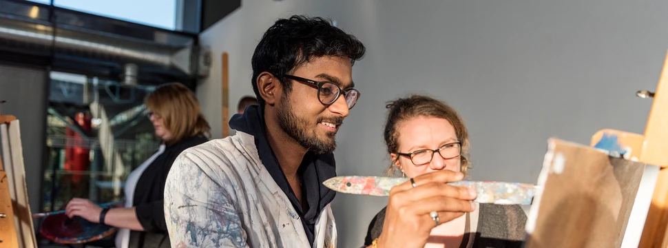 Zwei Menschen an einer Leinwand, die am Zeichnen sind