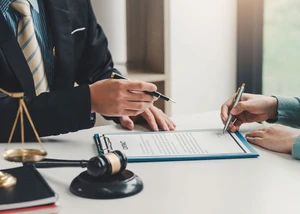Rechtsdokumente, Hammer und Waage auf einem Tisch, zwei Menschen