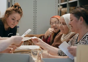 Mehrere Frauen, die in einem Raum Briefe lesen