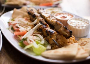 Die griechische Küche begeistert mit frischer Vielfalt, aromatischen Kräutern und mediterraner Leichtigkeit. Ein Teller mit Souvlaki und Salat