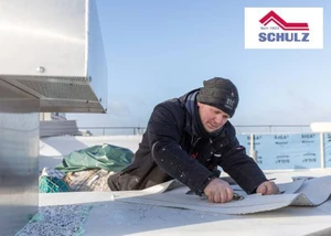 Handwerker verarbeitet Abdichtungsmaterial auf einem Flachdach.