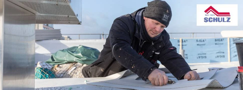 Handwerker verarbeitet Abdichtungsmaterial auf einem Flachdach.
