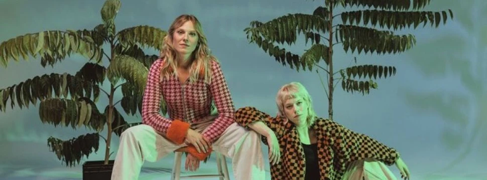 Zwei Frauen sitzen vor zwei Pflanzen