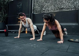 Zwei Menschen, die gerade Sport in einem Raum mit einem schwarzen Boden machen