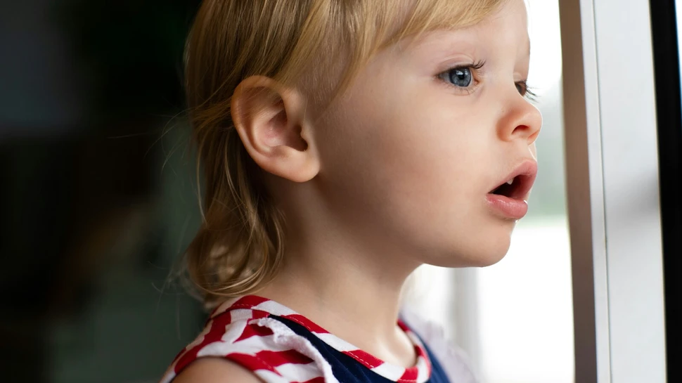 Kind guckt neugierig aus dem Fenster