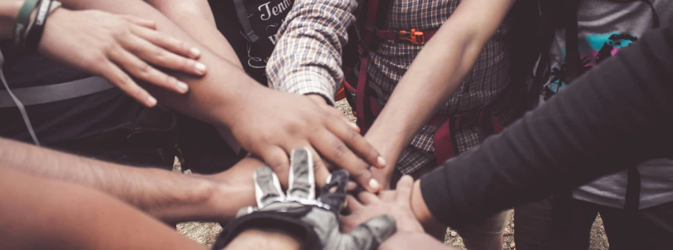 Mehrere Hände von Menschen, die in der Mitte des Bildes einen Haufen bilden