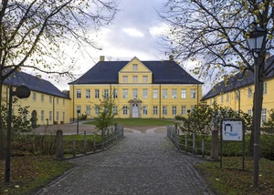 Prinzenpalais Schleswig in herbstlicher Atmosphäre. Gelbes Herrenhaus mit Kopfsteinpflasterweg und herbstlicher Umgebung in Schleswig.
