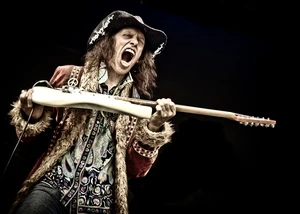 Mann hält eine Gitarre in den Händen und schreit