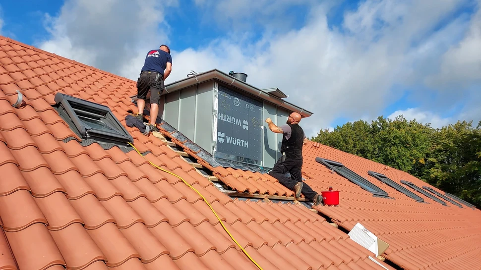 2 Dachdecker der Dachdeckerei Bente arbeiten auf dem Dach mit Dachziegeln