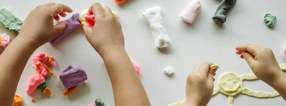Kunstwerke werden aus Knete hergestellt 4 Hände, die mit Knete über einer weißen Tischplatte Kunstwerke herstellen