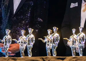 Mehrere kleine metallisch glänzende Preisfiguren, die auf einer Bühne stehen