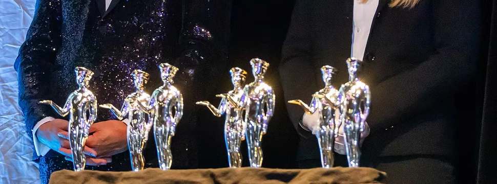 Mehrere kleine metallisch glänzende Preisfiguren, die auf einer Bühne stehen