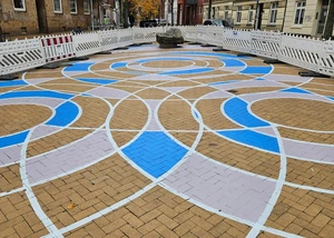 Bunt bemaltes Pflaster mit geometrischen Mustern auf dem Bahide-Arslan-Platz in urbaner Umgebung.