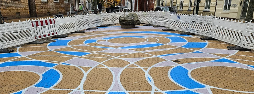 Bunt bemaltes Pflaster mit geometrischen Mustern auf dem Bahide-Arslan-Platz in urbaner Umgebung.