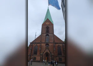 Ein großer Kirchturm in der Kieler Innenstadt mit Menschen im Vordergrund
