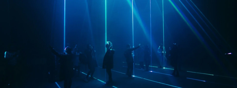 Menschen in einem Raum voller blauen Laserstrahlen