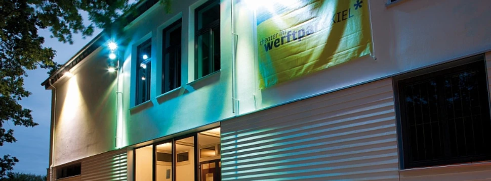 Ein weißes Gebäude, auf dem die Aufschrift "Theater im Werftpark" steht