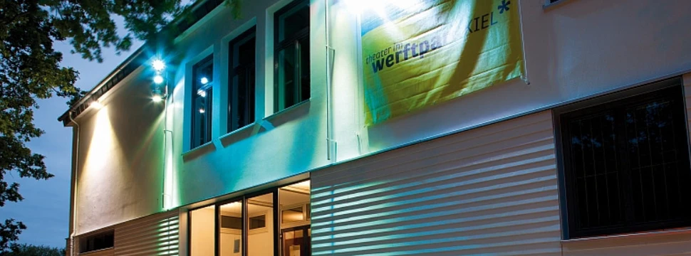 Ein weißes Gebäude, auf dem die Aufschrift "Theater im Werftpark" steht