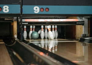 Eine Bowlingkugel wirft Pins um Eine Bowlingbahn aus Holz mit Pins und einer Bowlingkugel