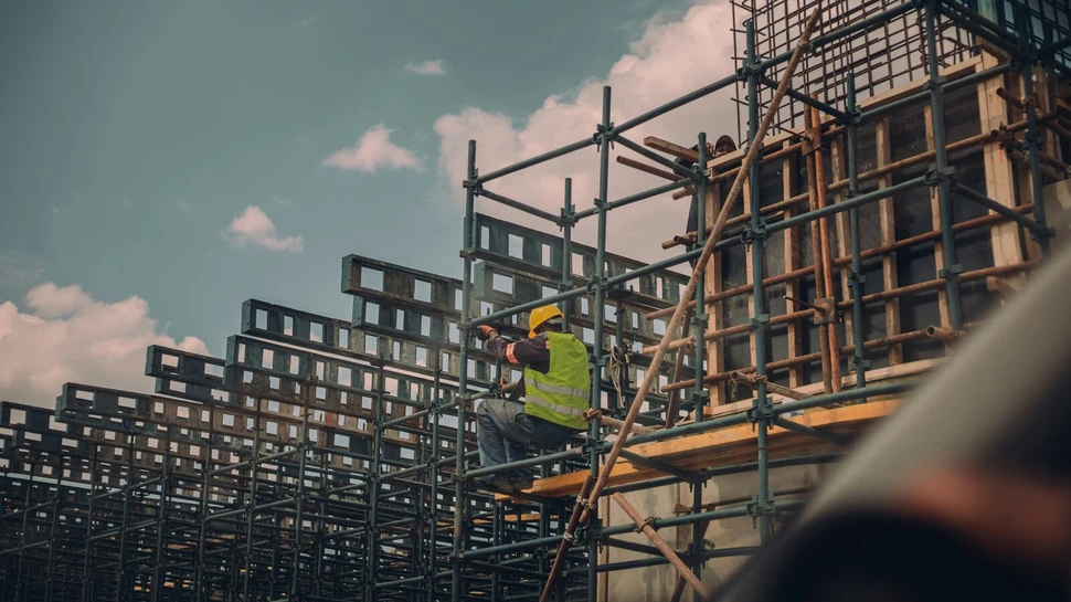 Ein Bauarbeiter sitzt auf einem Metallgerüst auf einer Baustelle