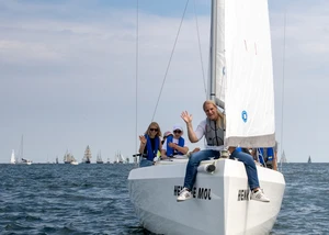 Ein Segelboot auf der Kieler Förde mit Menschen darauf und mit weiteren Booten im Hintergrund
