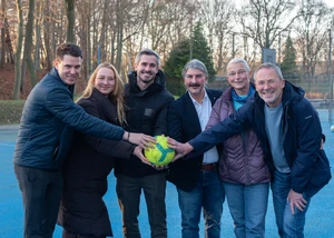 Mehrere Menschen in einem Park, die einen Ball in der Mitte halten