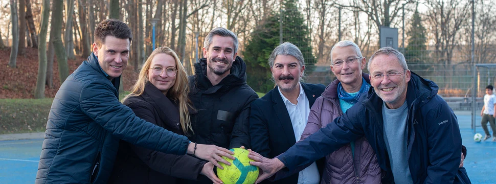 Mehrere Menschen in einem Park, die einen Ball in der Mitte halten